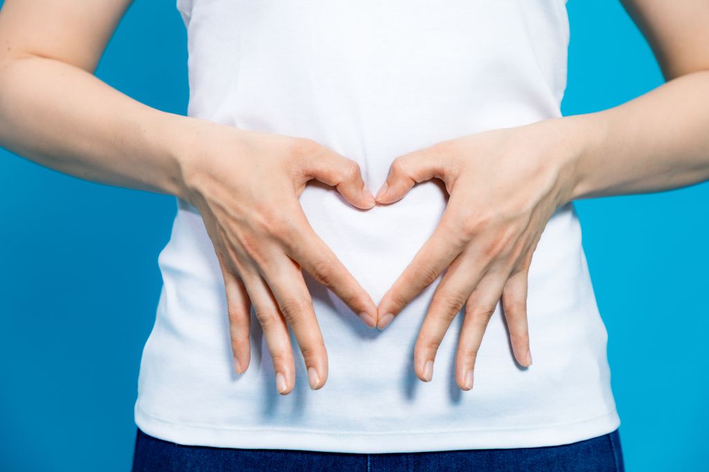 Person With their Hands In the shape of a heart over their gut