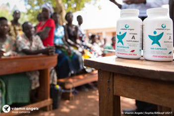 Bottle With Vitamin Angles Logo and Children In The Background